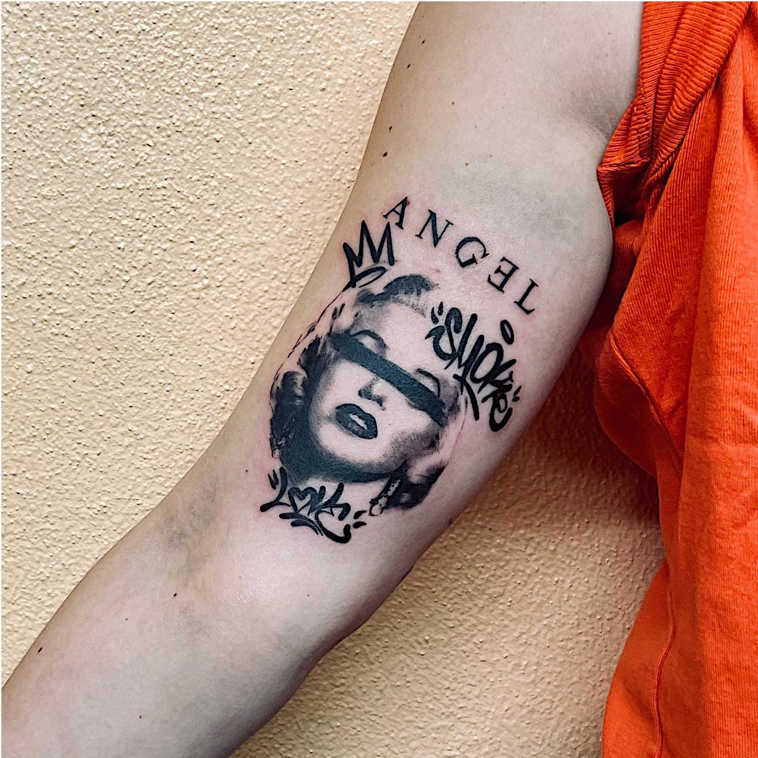 Un tatouage avec la tête de Marylin Monroe et des écritures façon tag