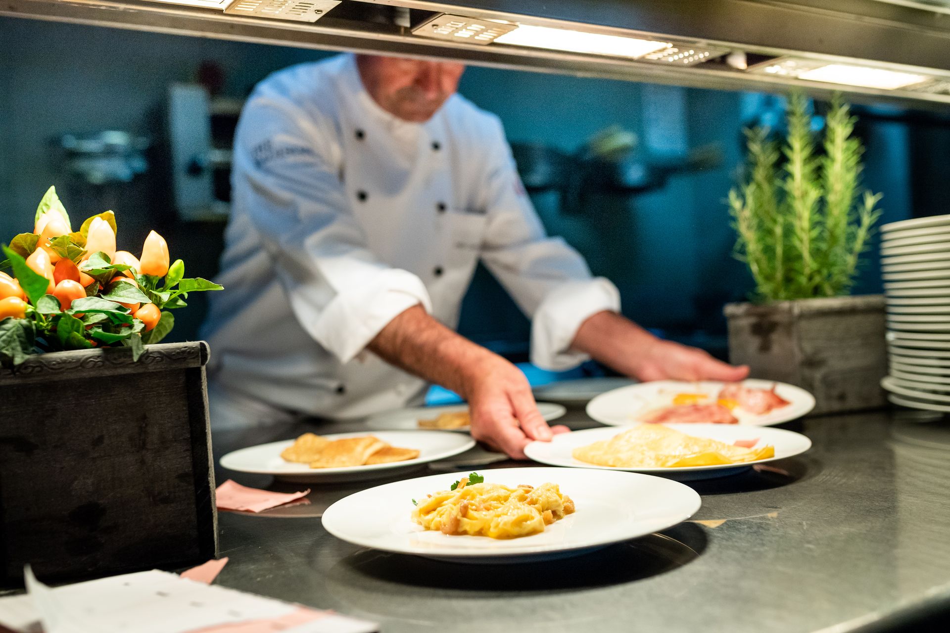 A chef is preparing food on a counter in a restaurant kitchen.