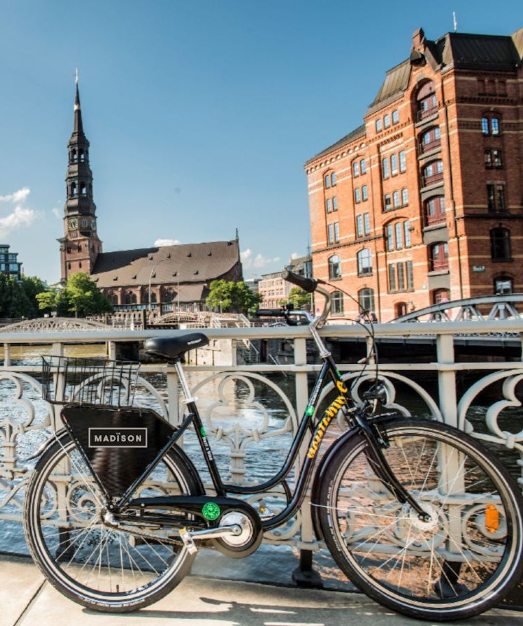 A bicycle is parked on a bridge in front of a brick building.