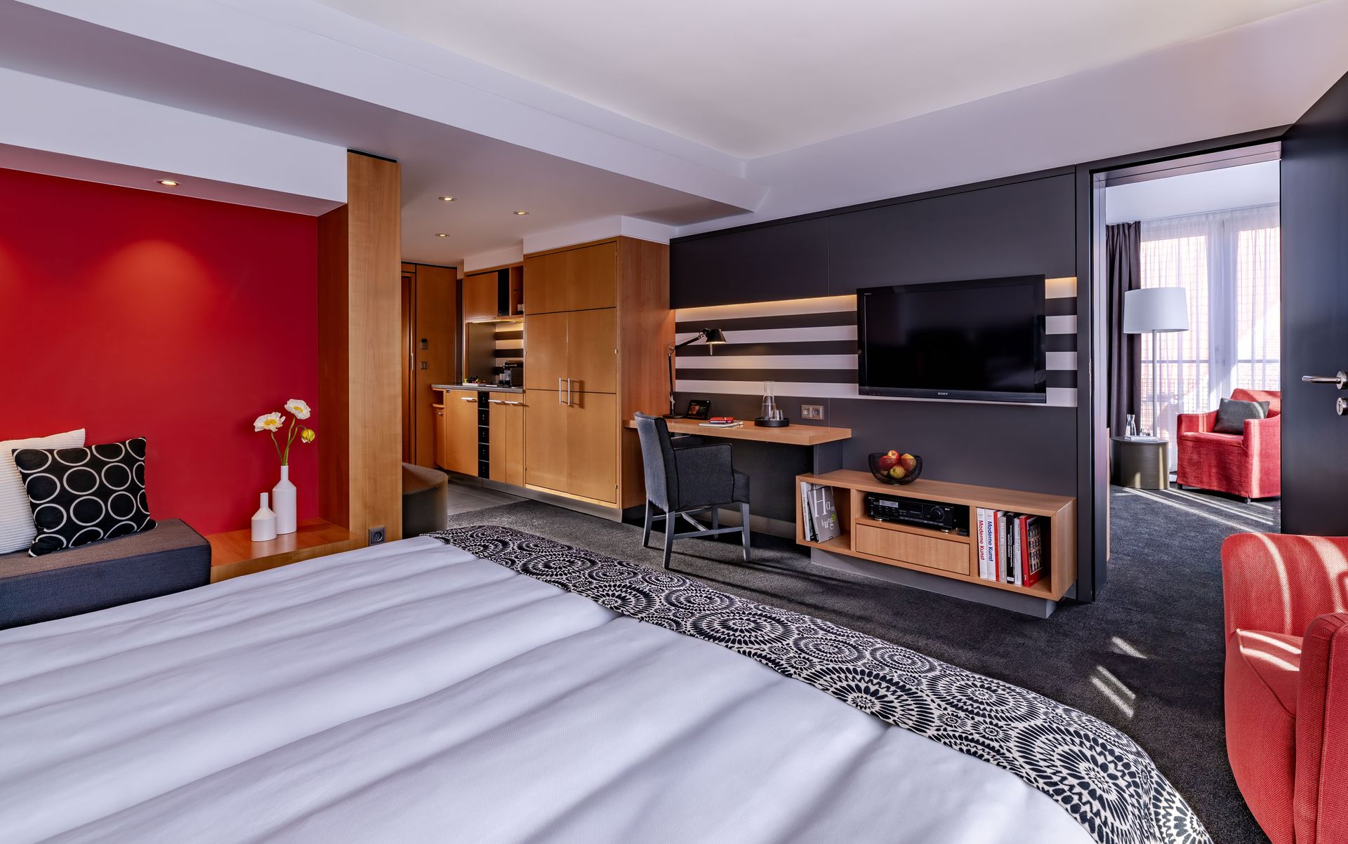 A hotel room with a king size bed , television , desk and chairs.