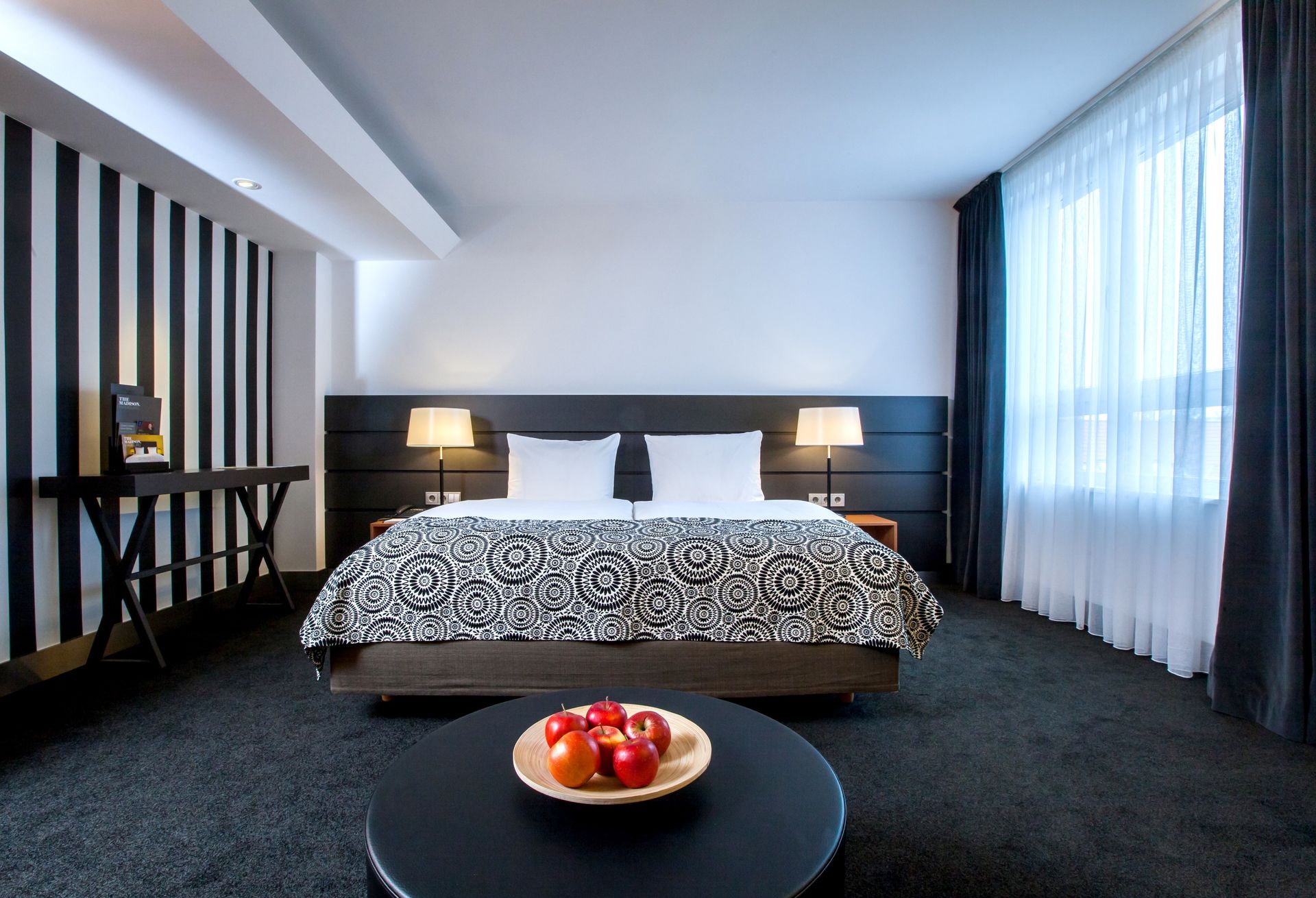 A hotel room with a king size bed and a bowl of apples on the table