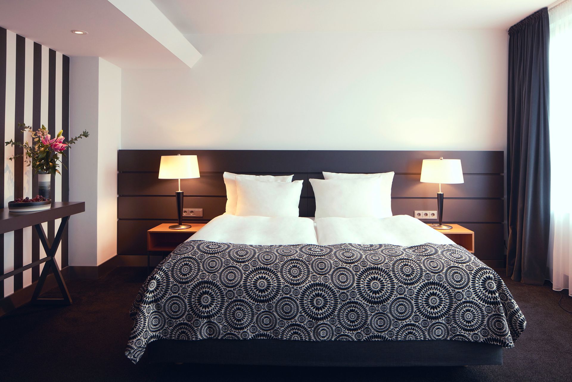 A hotel room with a bed and two lamps