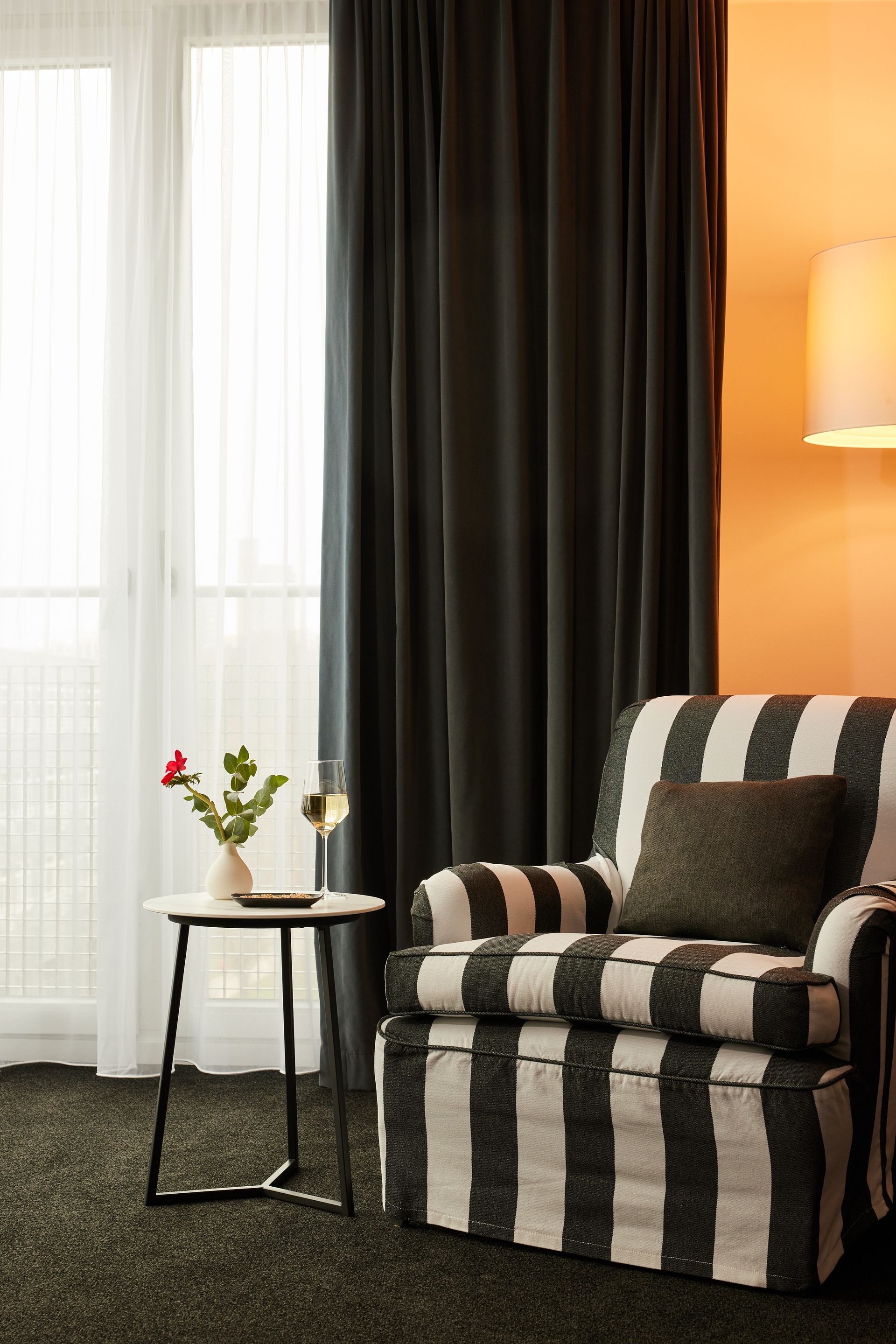 A black and white striped chair is in a living room next to a window.