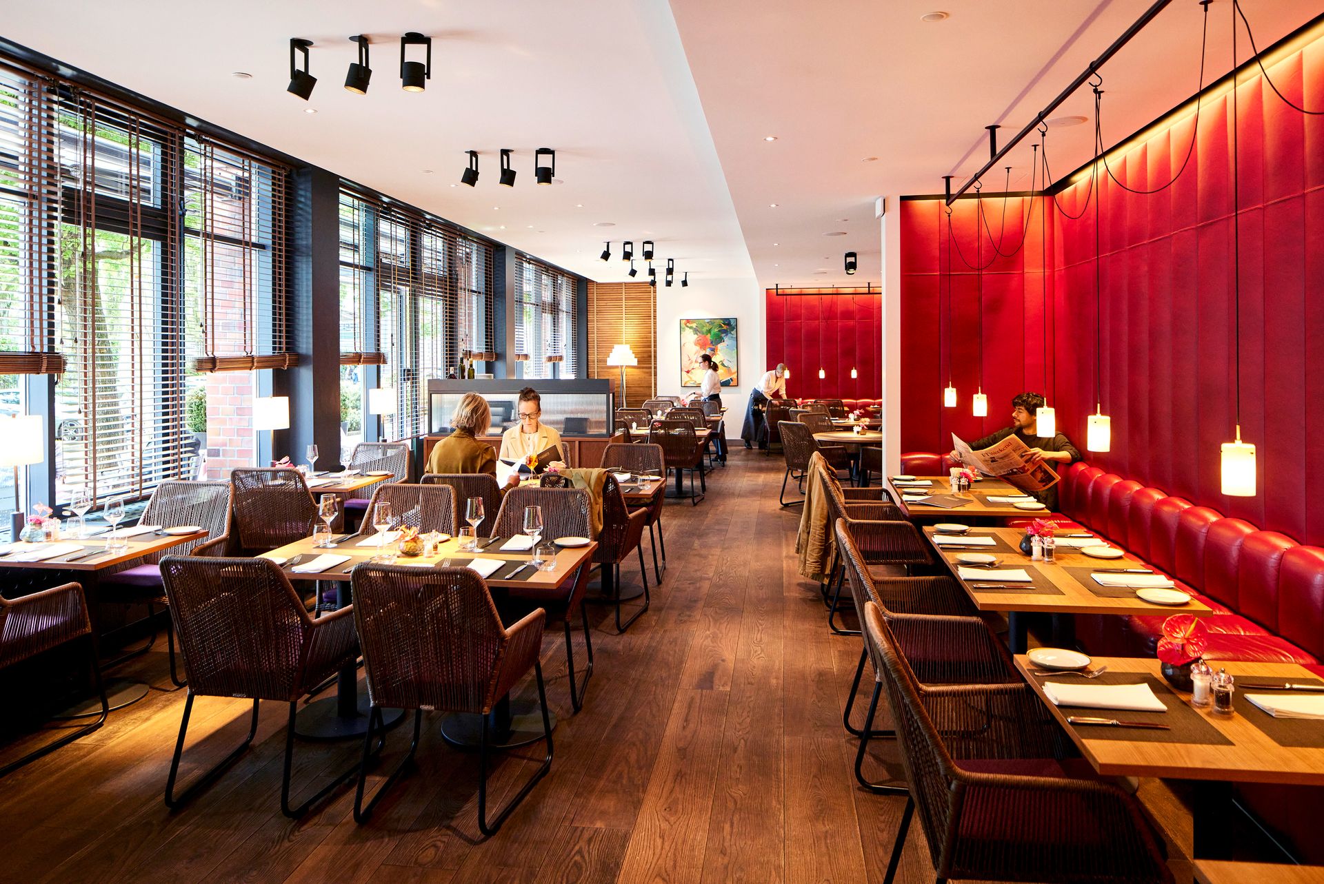 A restaurant with tables and chairs and a red wall
