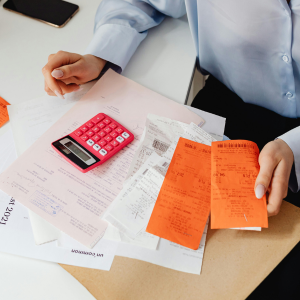 Una persona está sentada en un escritorio con una calculadora y recibos.