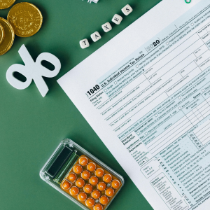 Un formulario de impuestos con una calculadora y monedas sobre una mesa.