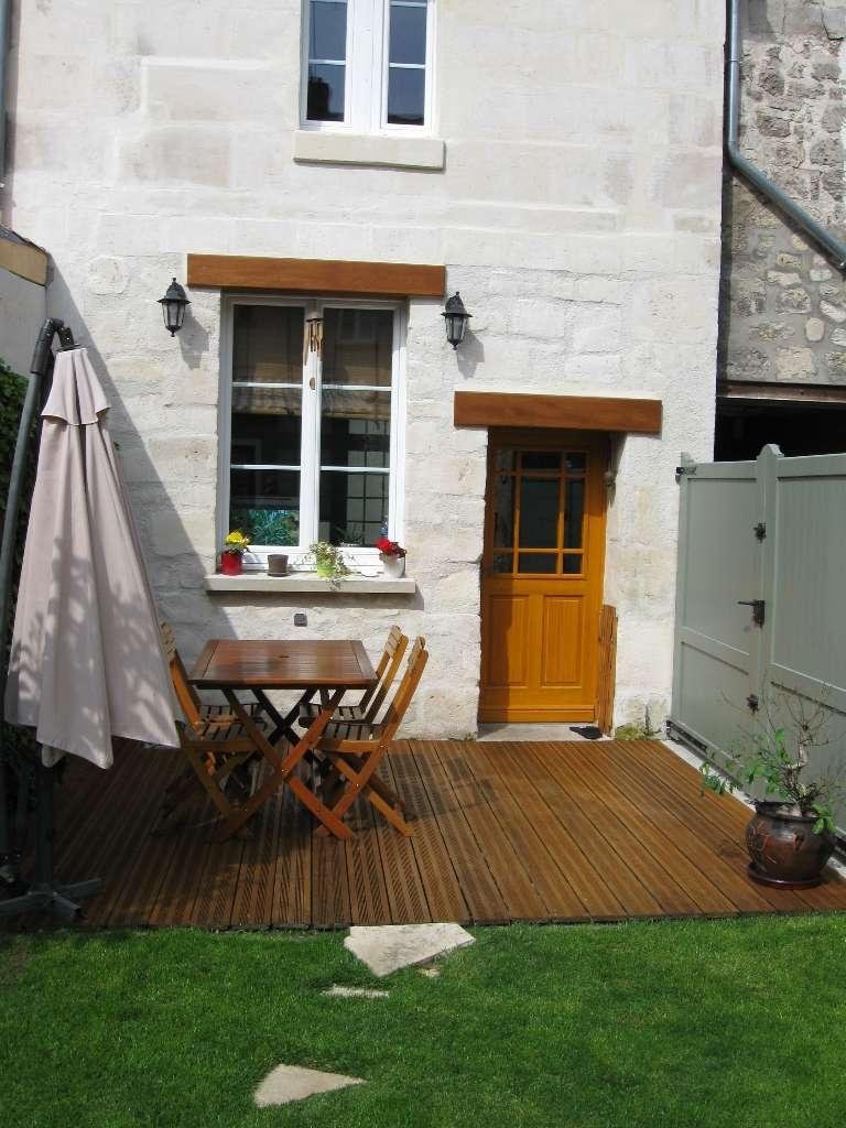 Porte en bois et terrasse en bois devant une maison en pierre