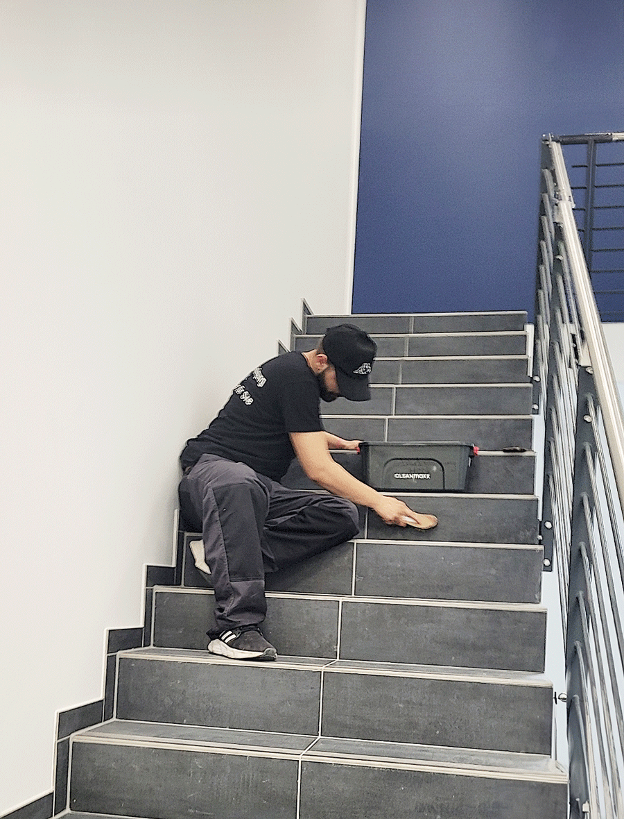 Ein Mann sitzt auf einer Treppe und hält einen Werkzeugkasten.