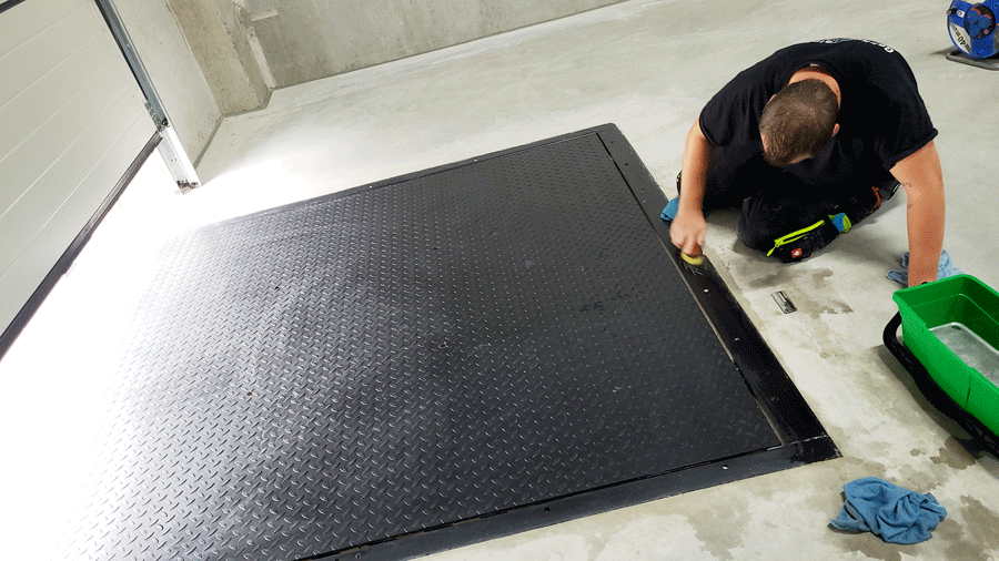 Ein Mann reinigt eine schwarze Matte auf dem Boden.