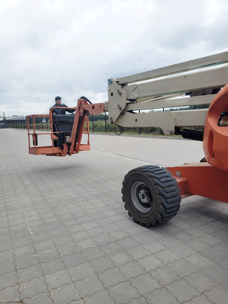 Ein Mann fährt einen Kran auf einer Ziegelsteinstraße.