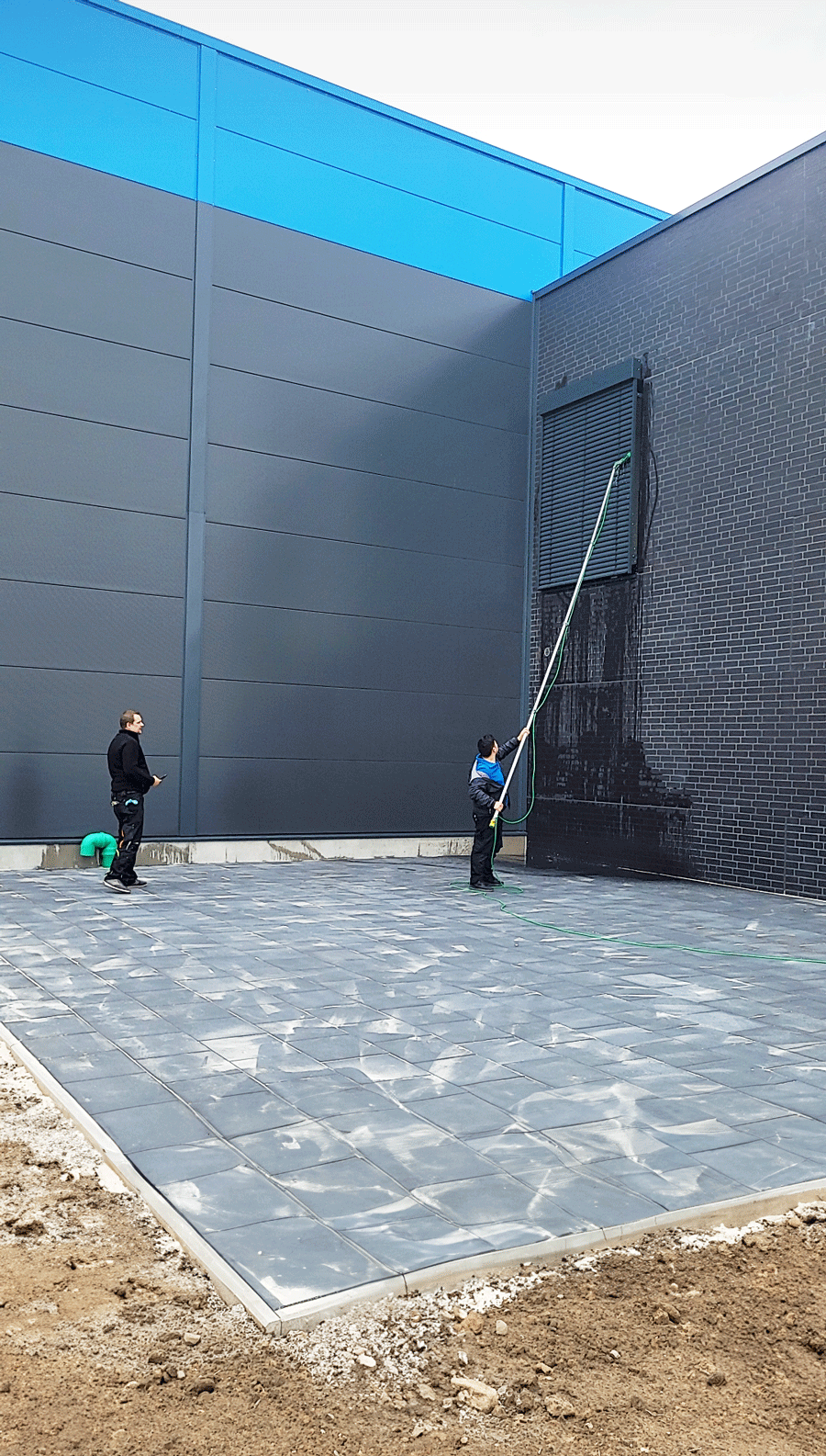 Eine Gruppe von Menschen steht vor einem großen Gebäude und reinigt dieses.