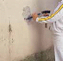 Un hombre con un traje blanco está enyesando una pared.