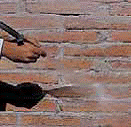 Un hombre con traje y corbata está parado frente a una pared de ladrillos.