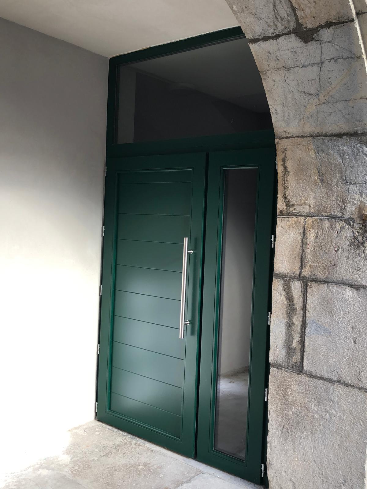 Une porte de garage fermée, de couleur, avec des panneaux horizontaux et une poignée centrale.