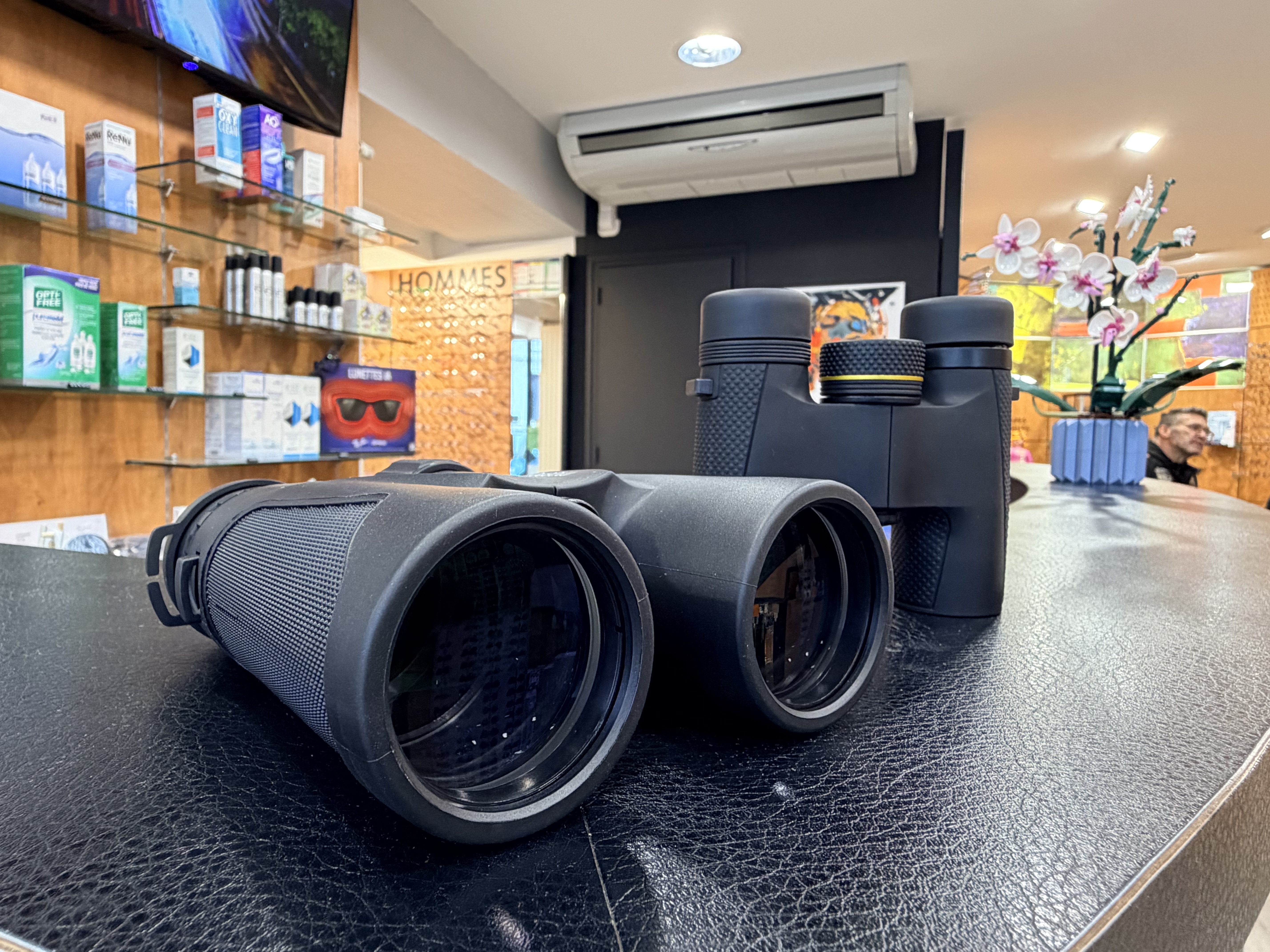 Des jumelles de théâtre posées sur une surface de velours rouge, devant un rideau rouge.