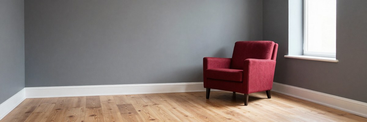 Fertig renoviertes Wohnzimmer mit anthrazitfarbenen und hellgrauen Wänden und rotem Sessel