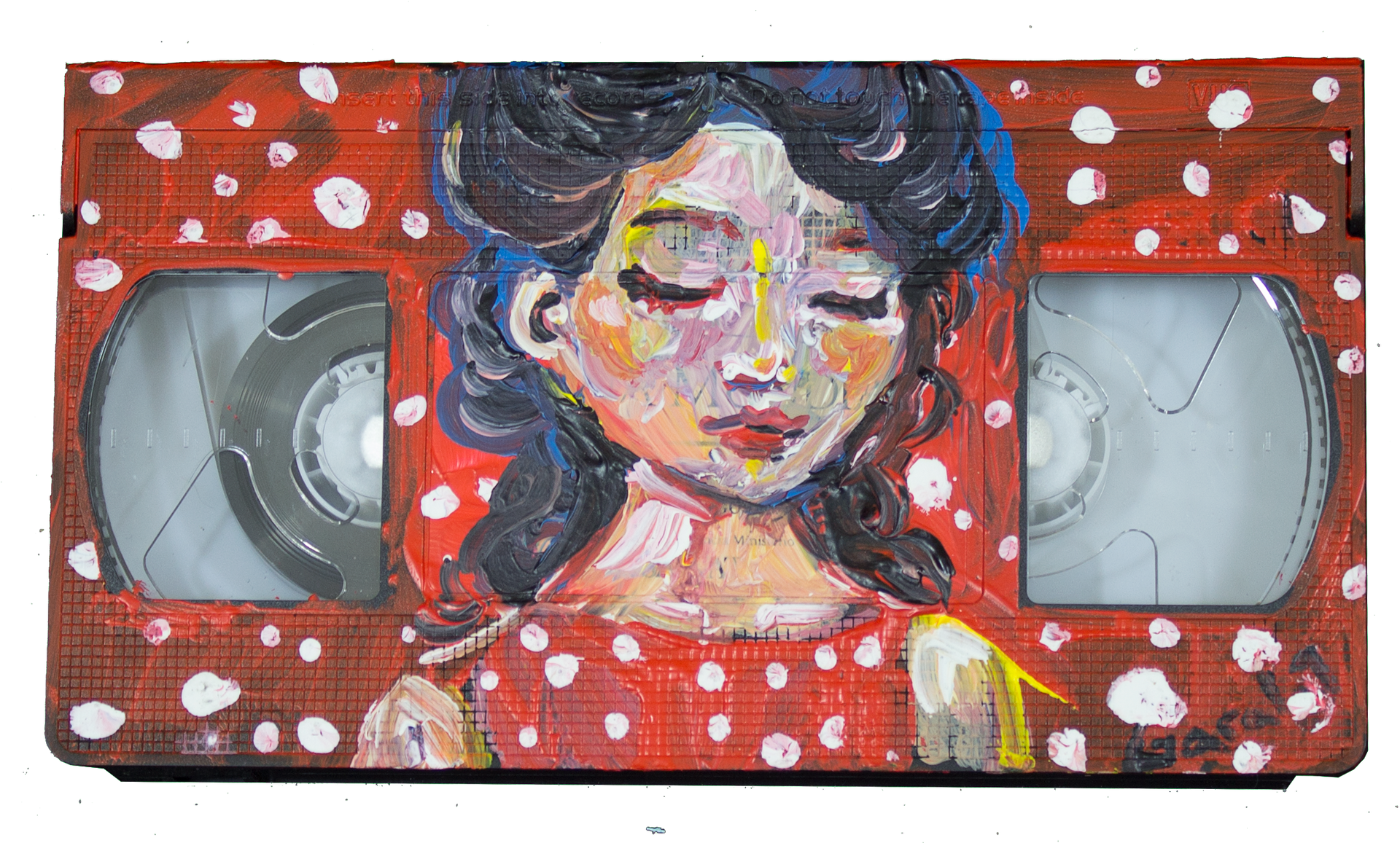 Cinta VHS pintada con el rostro de una mujer, vestido rojo, ojos cerrados y sobre un fondo de lunares rojos.