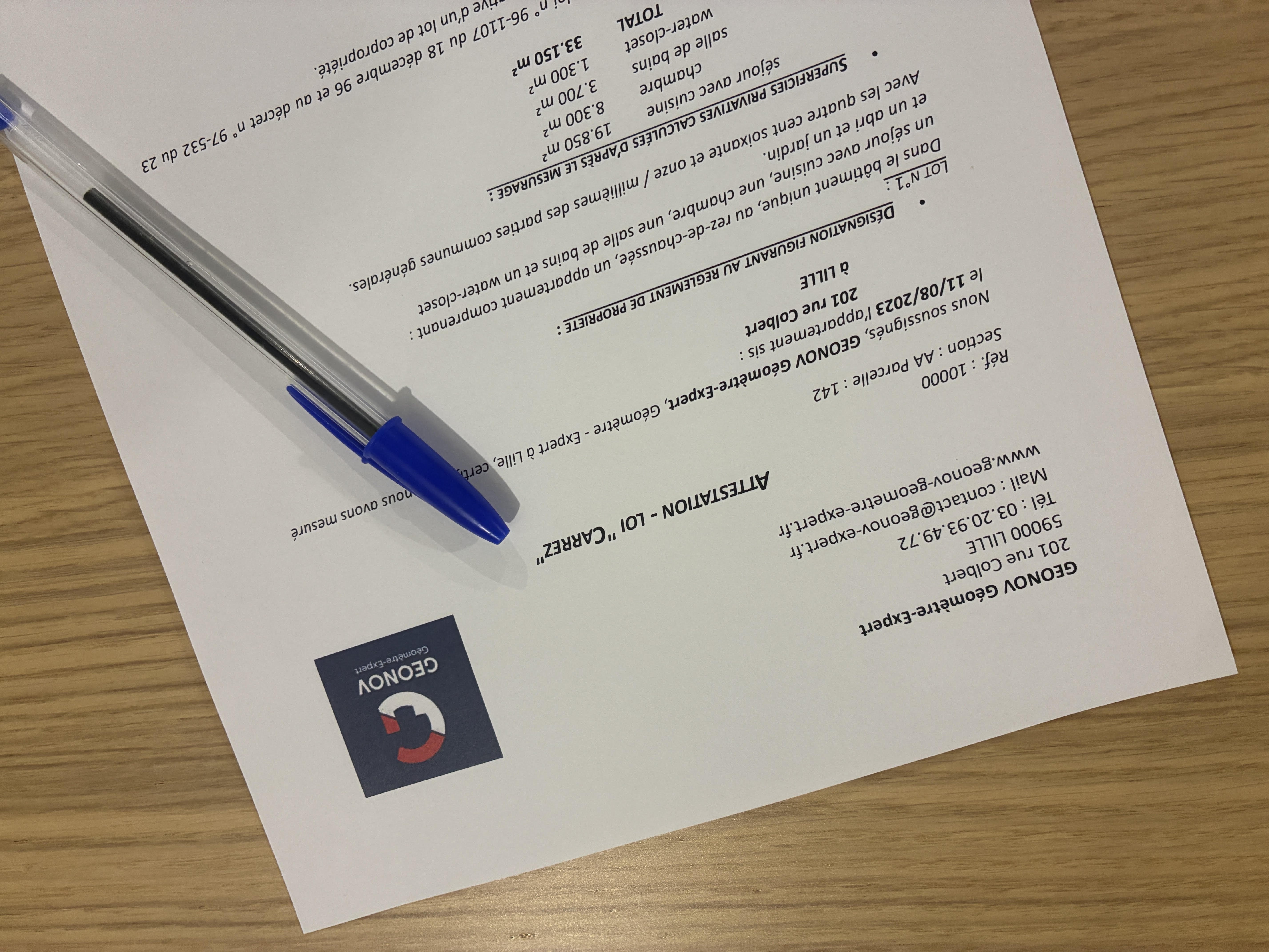 Un document écrit au stylo bleu sur une surface en bois.