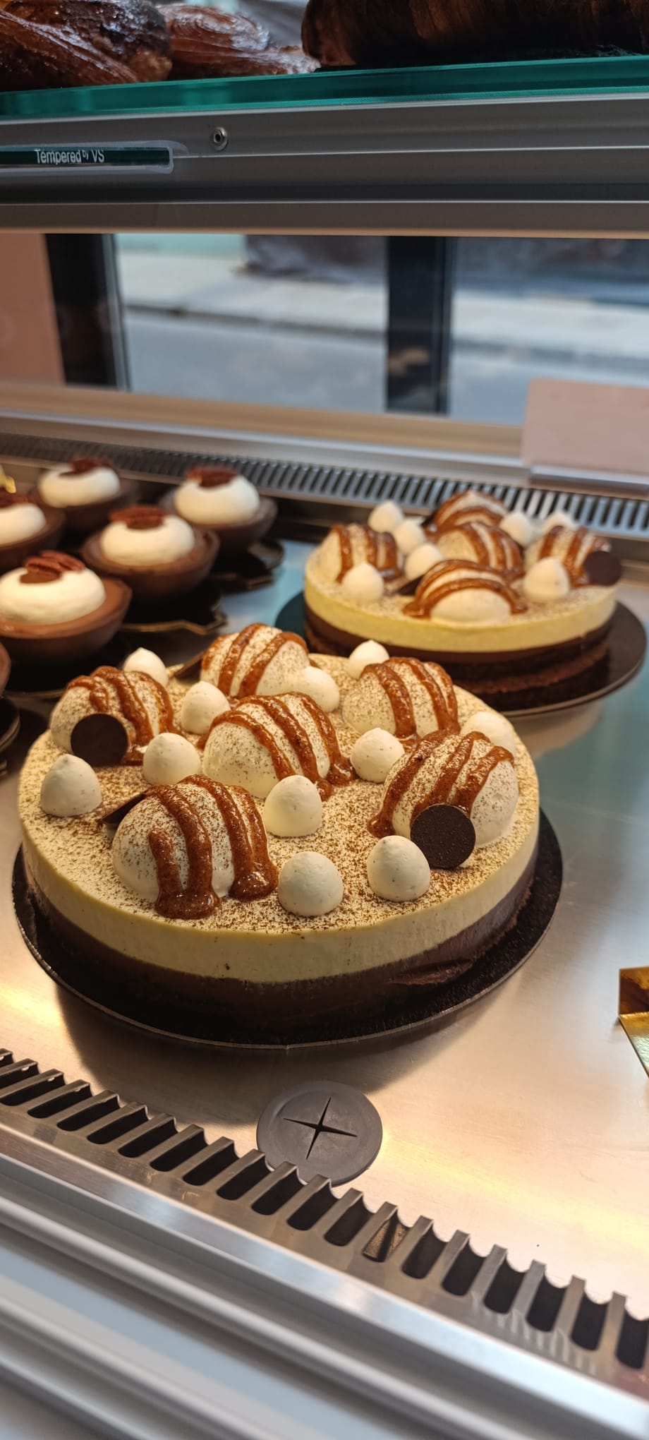 Gâteau rond décoré de rosettes de glaçage blanc, présenté sur un plateau doré, parsemé de vermicelles et doté d'un centre glacé.