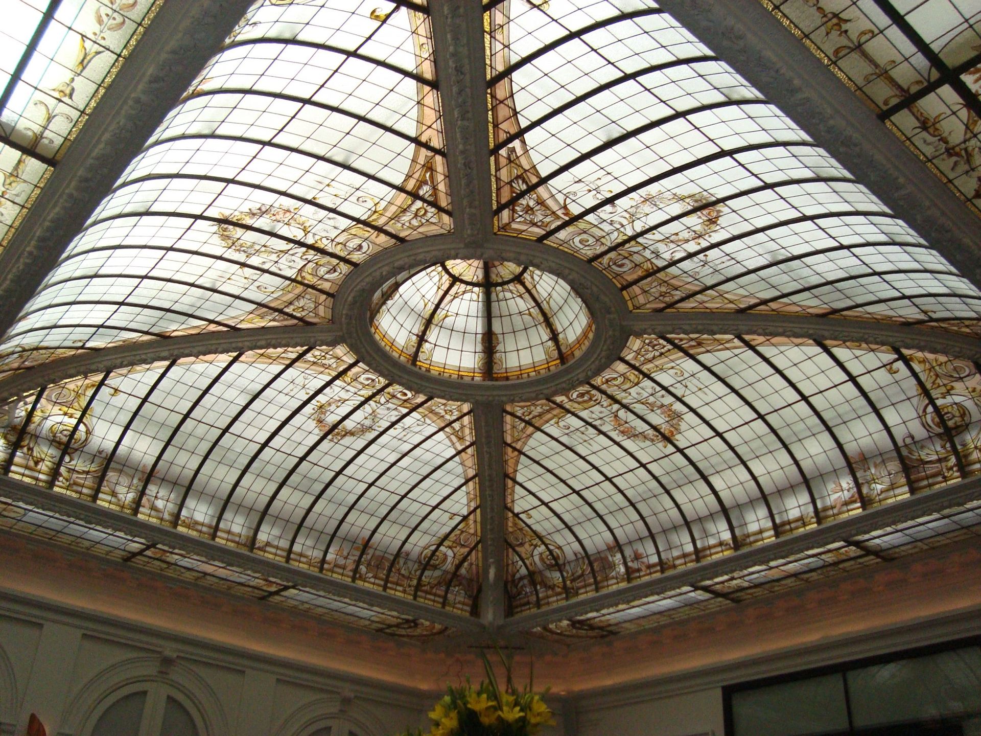 Plafond de verre orné d'une arche radiale, de motifs dorés complexes et d'un détail central circulaire.