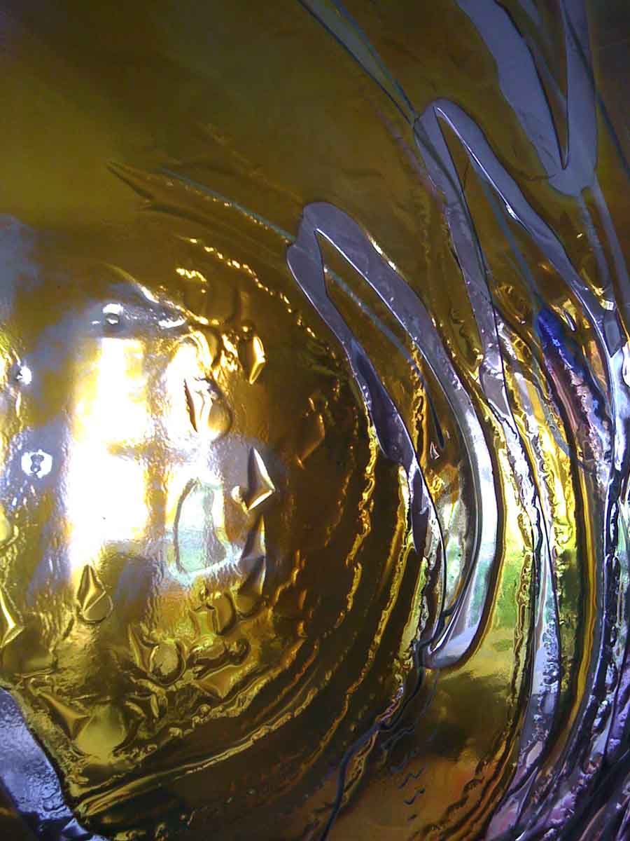 Vitrail en verre doré et blanc, jouant avec les reflets de la lumière pour créer des motifs ondulés.