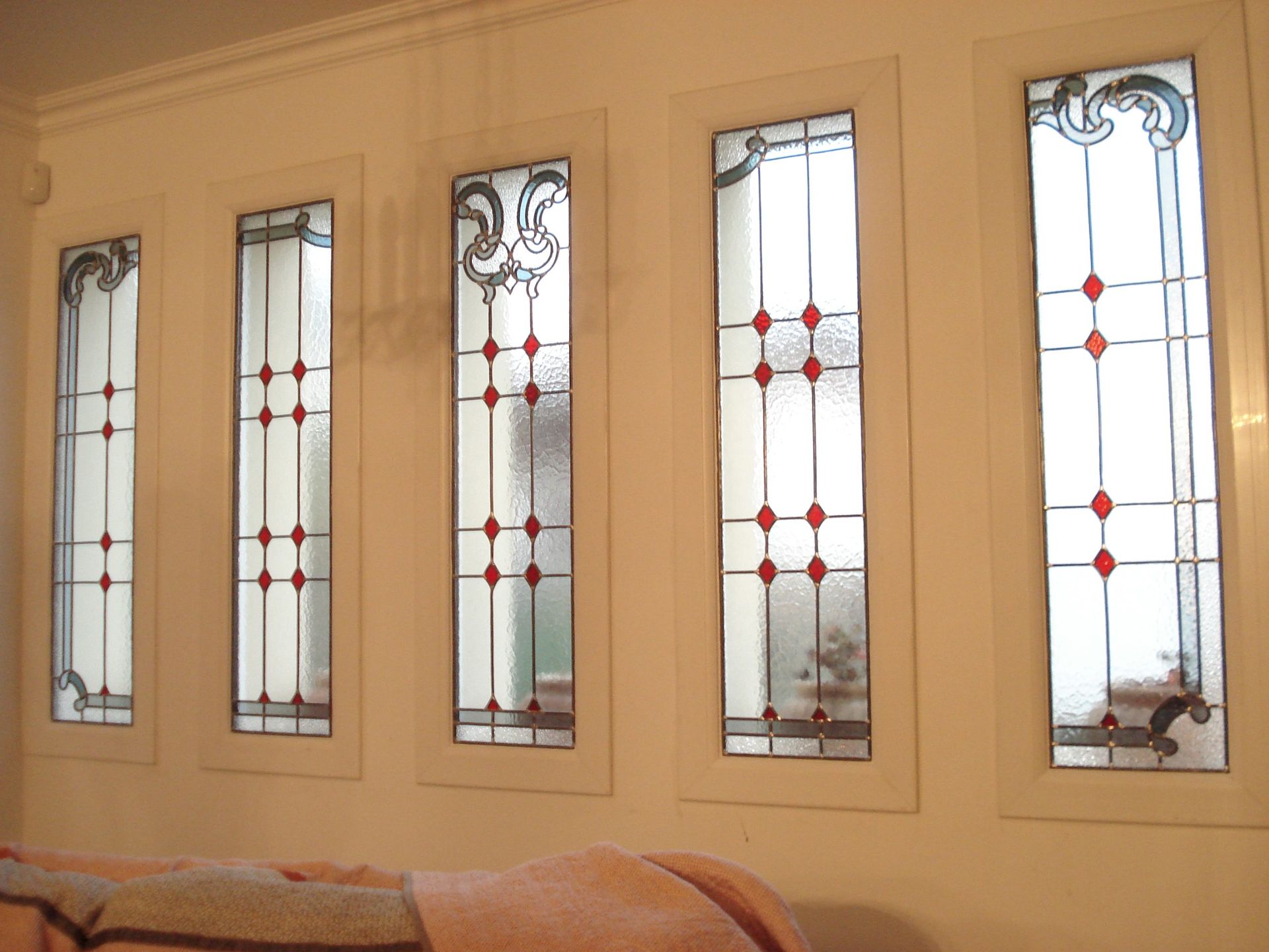 Cinq vitraux rectangulaires à pois rouges, cadres blancs et ornements décoratifs en partie supérieure.