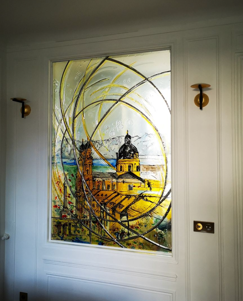 Vitrail représentant un bâtiment jaune avec un dôme, des volutes et un littoral au loin.