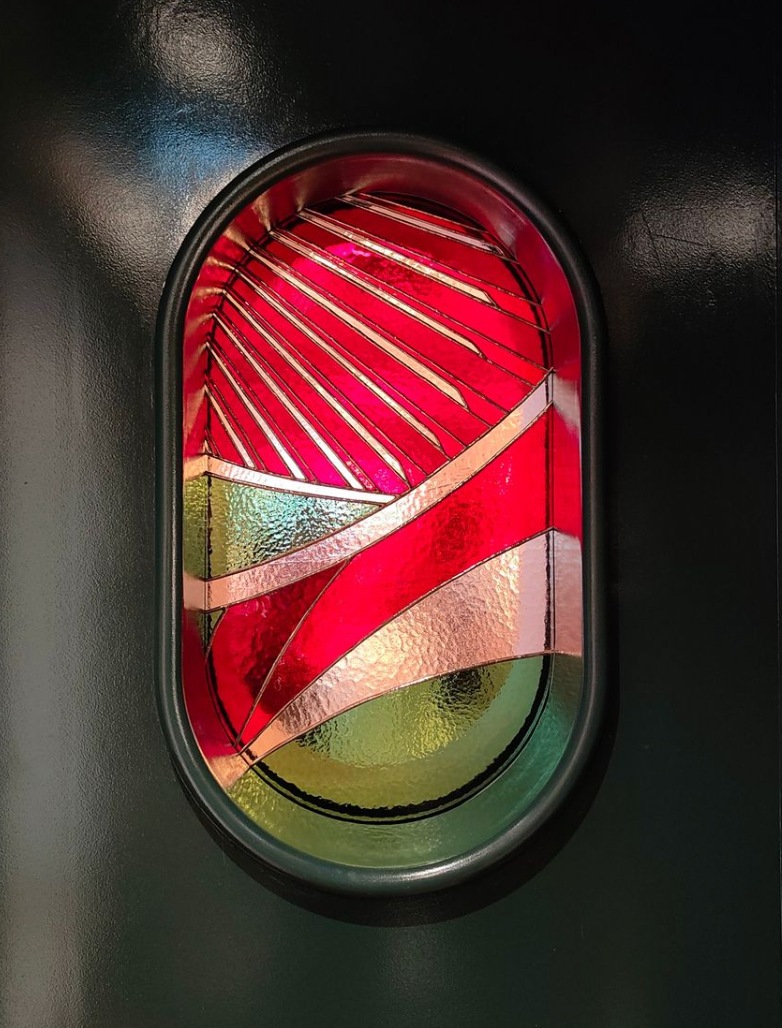 Fenêtre ovale ornée d'un décor coloré et superposé rouge et or.