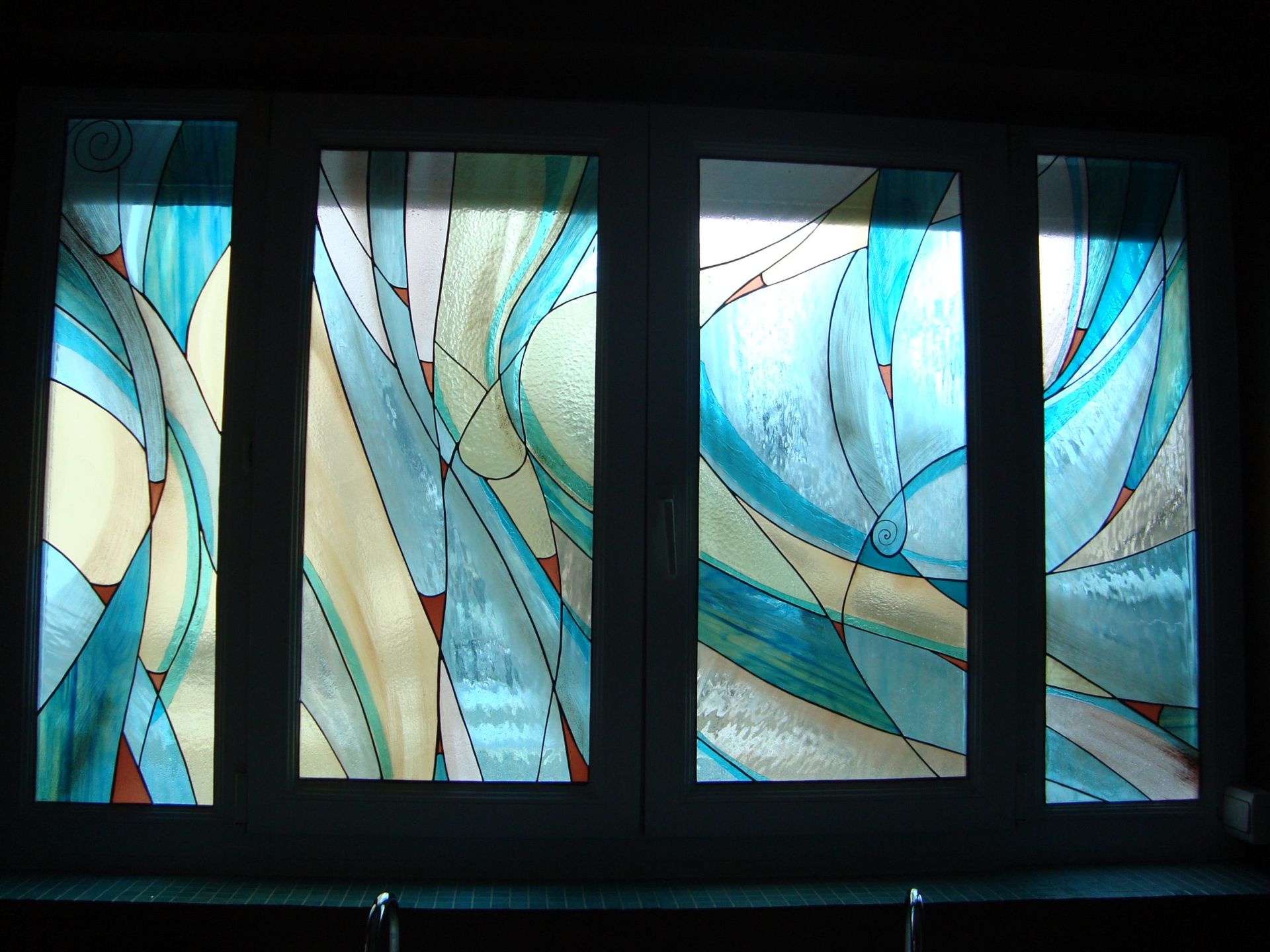Vitrail à motifs abstraits tourbillonnants bleus et jaunes, avec des séparations sombres.