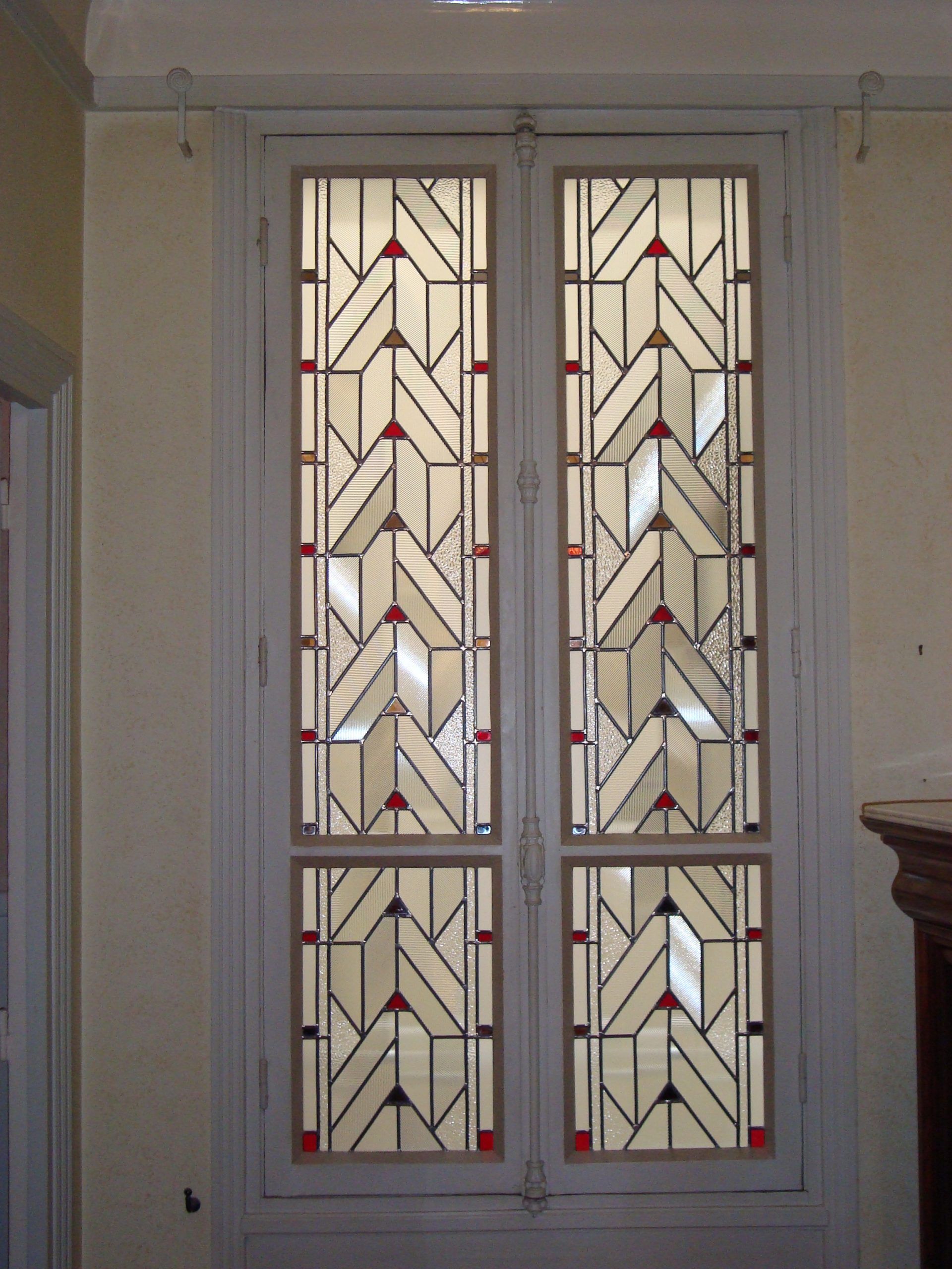 Fenêtre à deux panneaux ornée d'un vitrail géométrique blanc, rouge et noir.