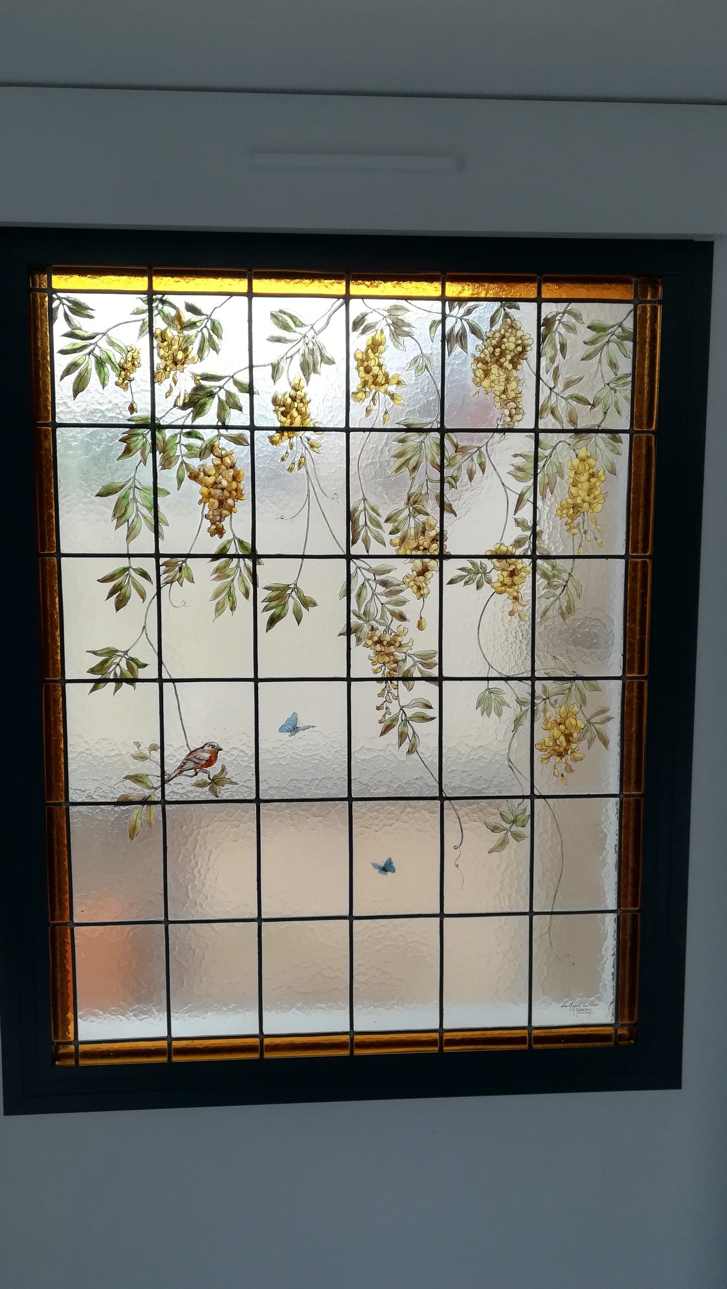 Vitrail à motif quadrillé et décor floral orné de fleurs jaunes et de feuilles vertes.