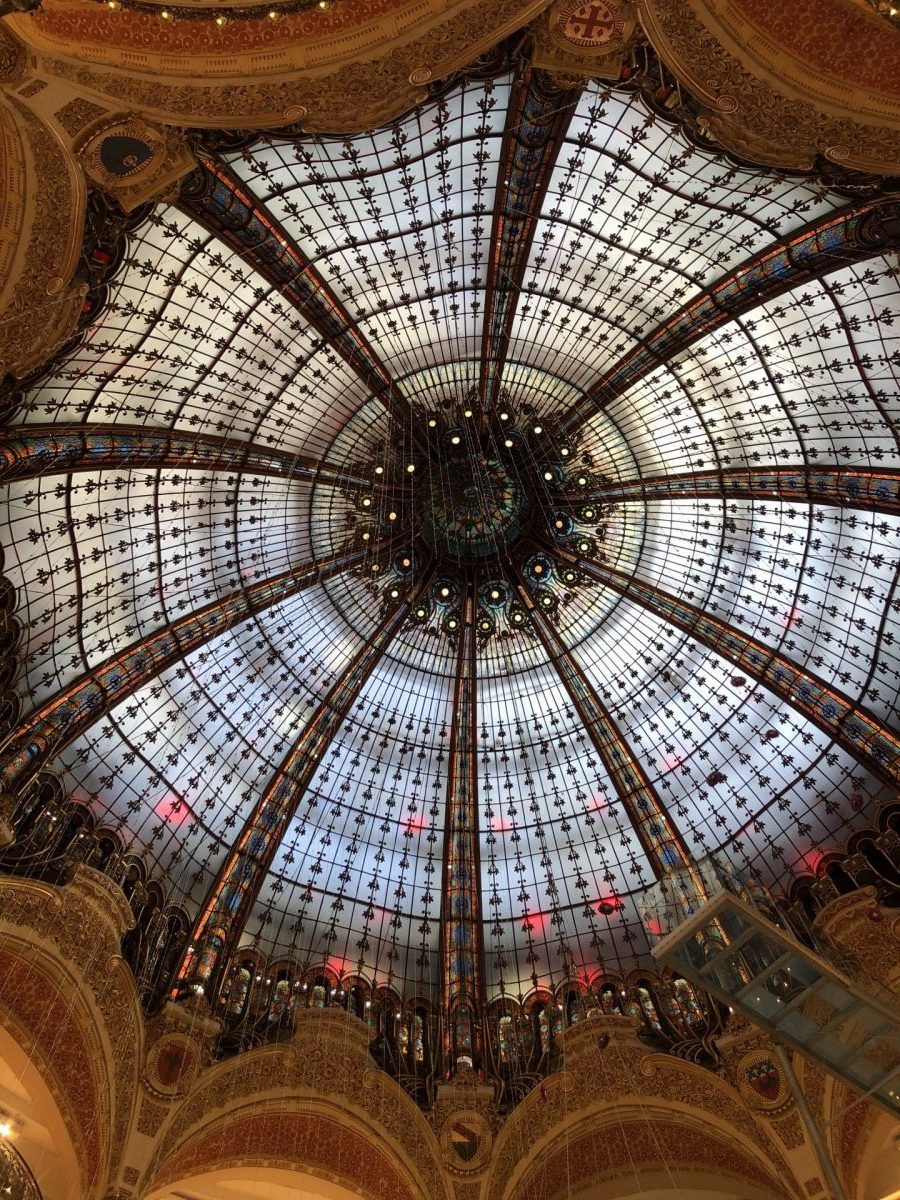 Plafond en dôme de verre orné de motifs géométriques complexes dans un bâtiment grandiose.