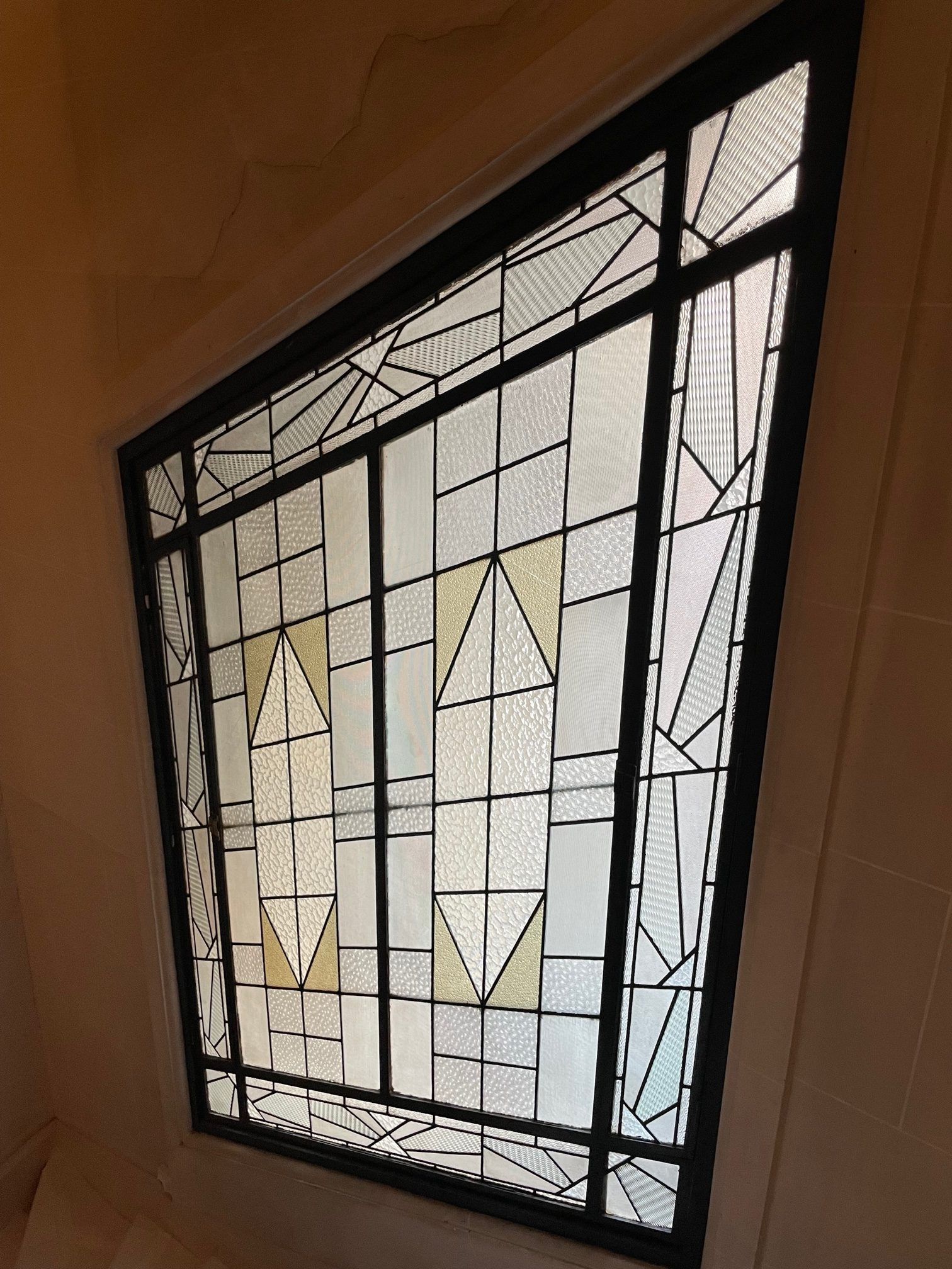 Vitrail géométrique à grille noire, avec des accents crème et jaune.