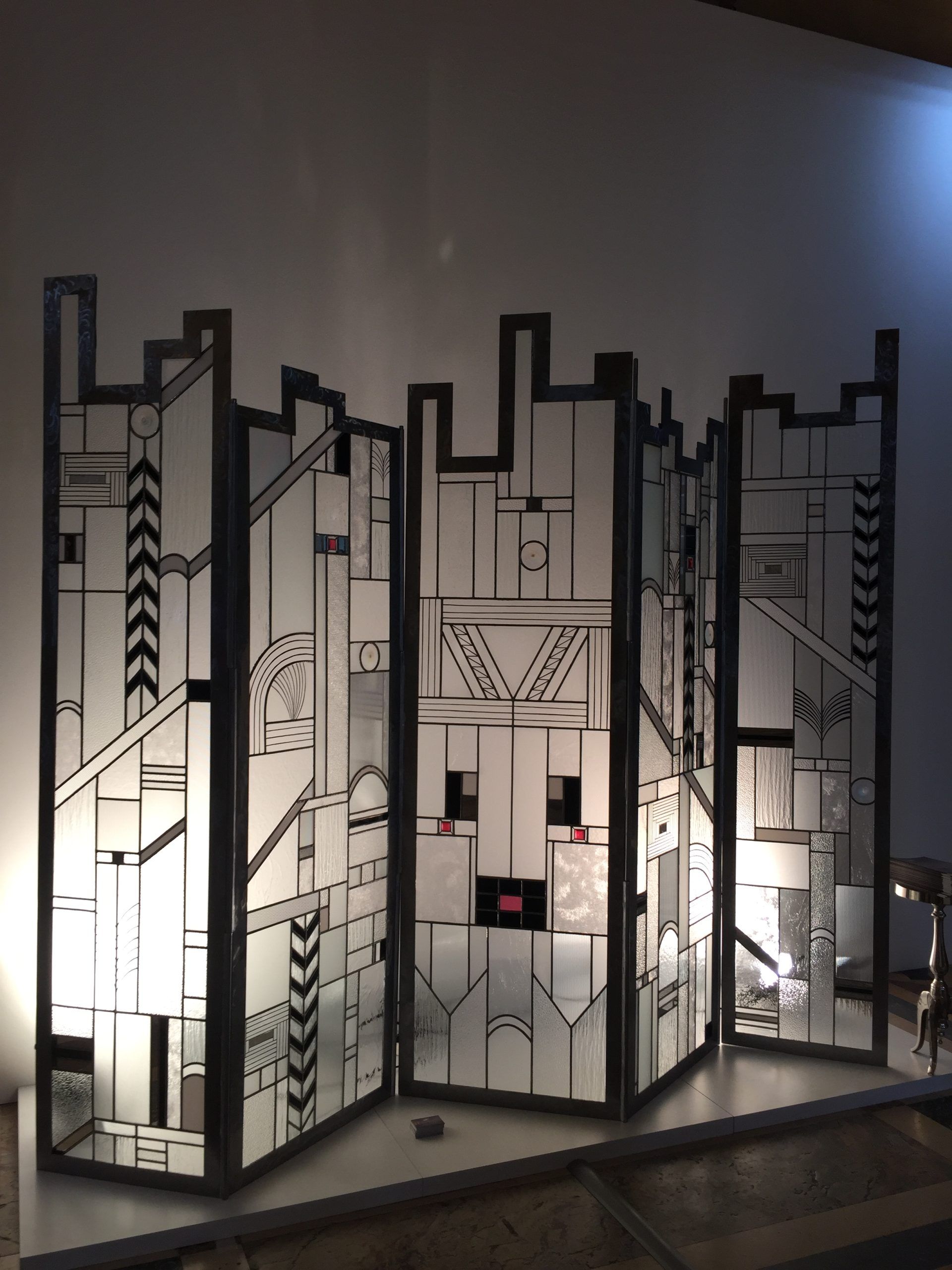 Écran en verre abstrait à motif géométrique noir, rétroéclairé sur une surface claire.