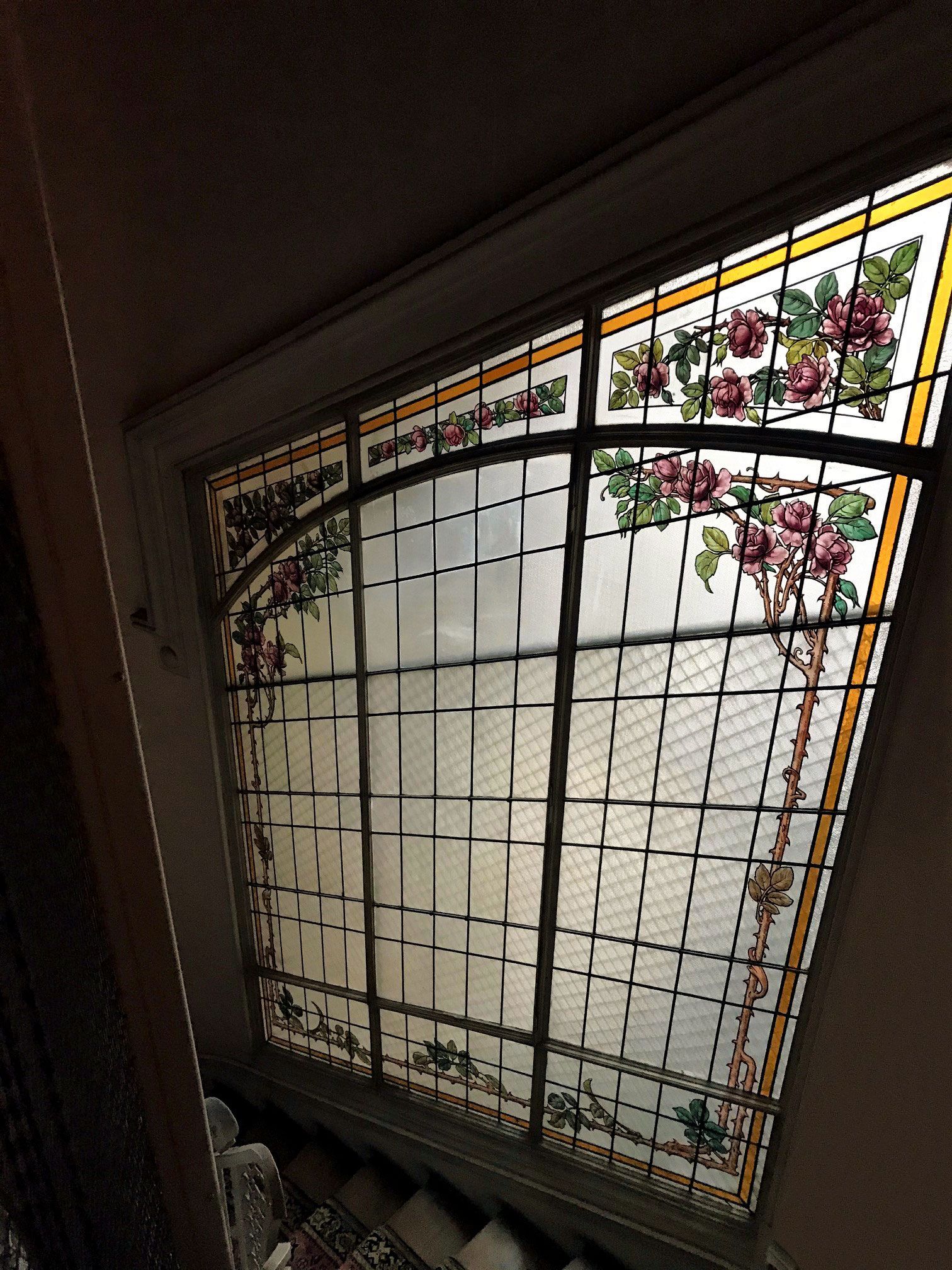 Vitrail orné de roses roses et de feuilles vertes, disposées en grille.