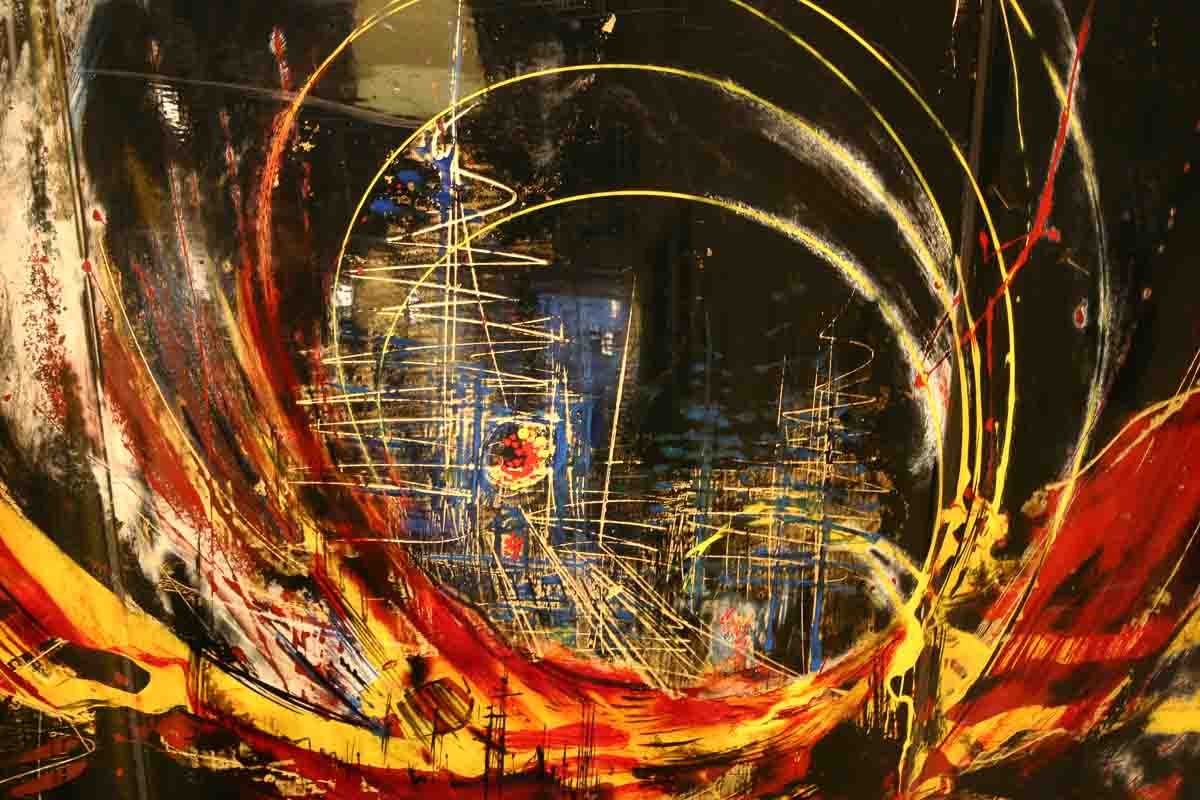 Vitrail abstrait représentant la silhouette d'une ville, avec des lignes tourbillonnantes rouges, jaunes et blanches sur un fond sombre.