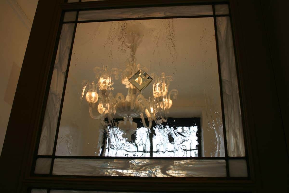 Fenêtre en verre biseauté laissant apparaître un lustre.