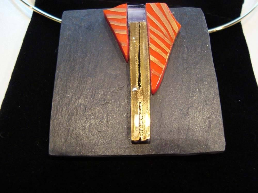 Collier pendentif carré à fond ardoise, motif géométrique or et orange, ras-de-cou argenté.