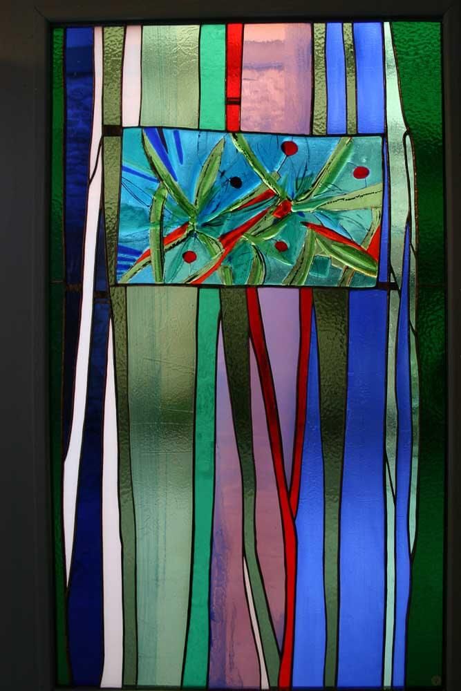 Panneau de vitrail avec un motif central rectangulaire bleu et des rayures verticales de couleurs variées.