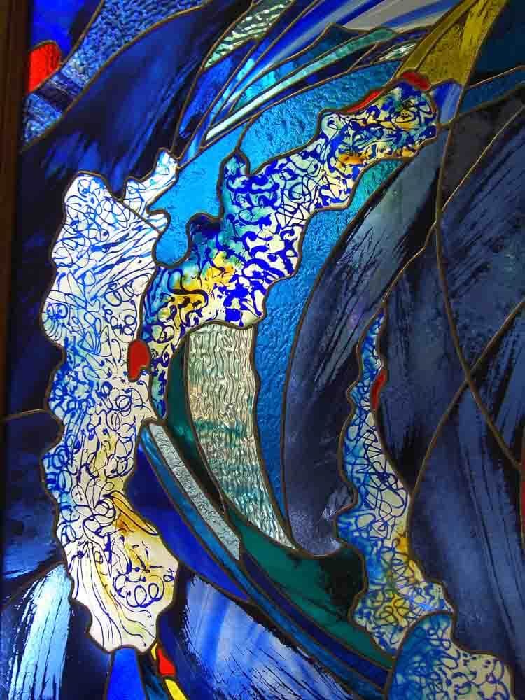 Vitrail, tourbillons de bleu, sections à motifs blancs et touches de rouge et de vert.