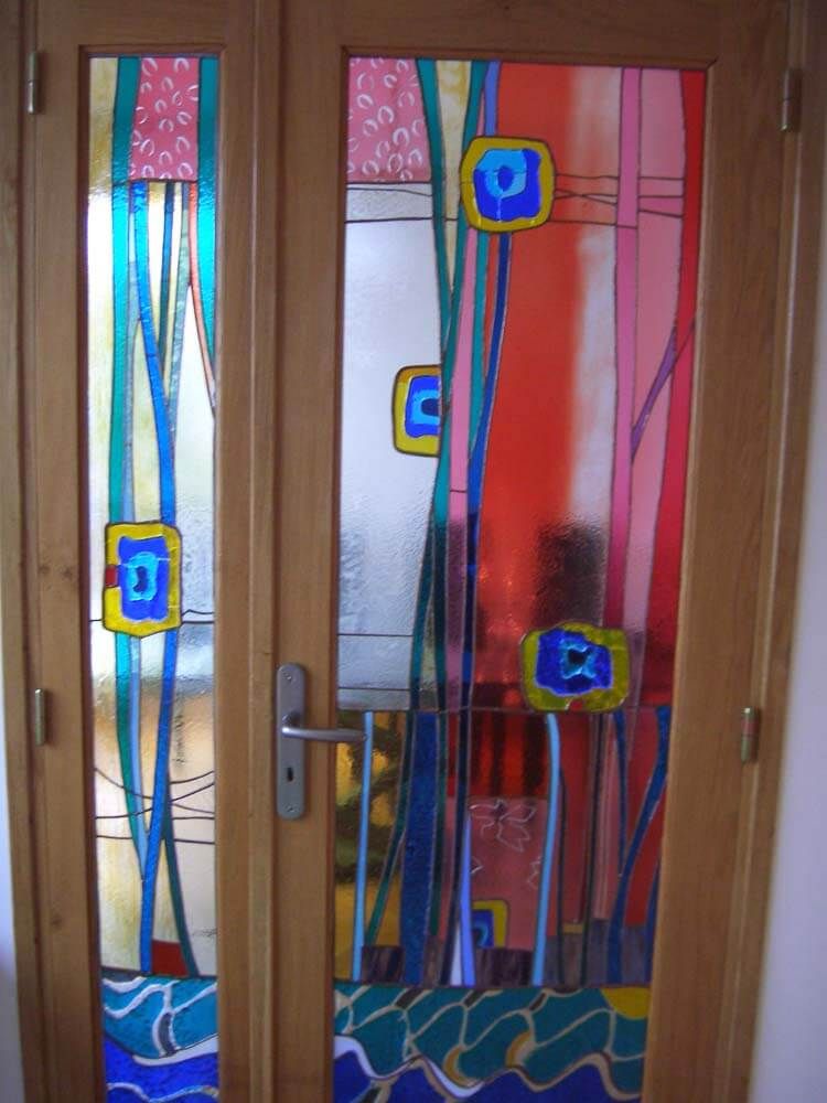 Porte en vitrail ornée de motifs floraux colorés sur un cadre en bois.