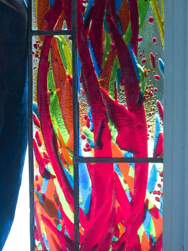 Vitrail à motif abstrait rouge, bleu, vert et orange.