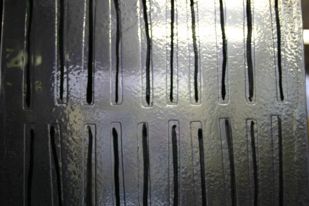 Surface en verre et motifs noirs avec des fentes verticales.