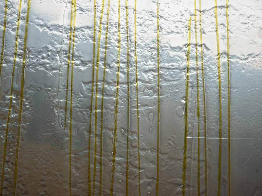 Surface en verre avec des stries verticales jaunes.