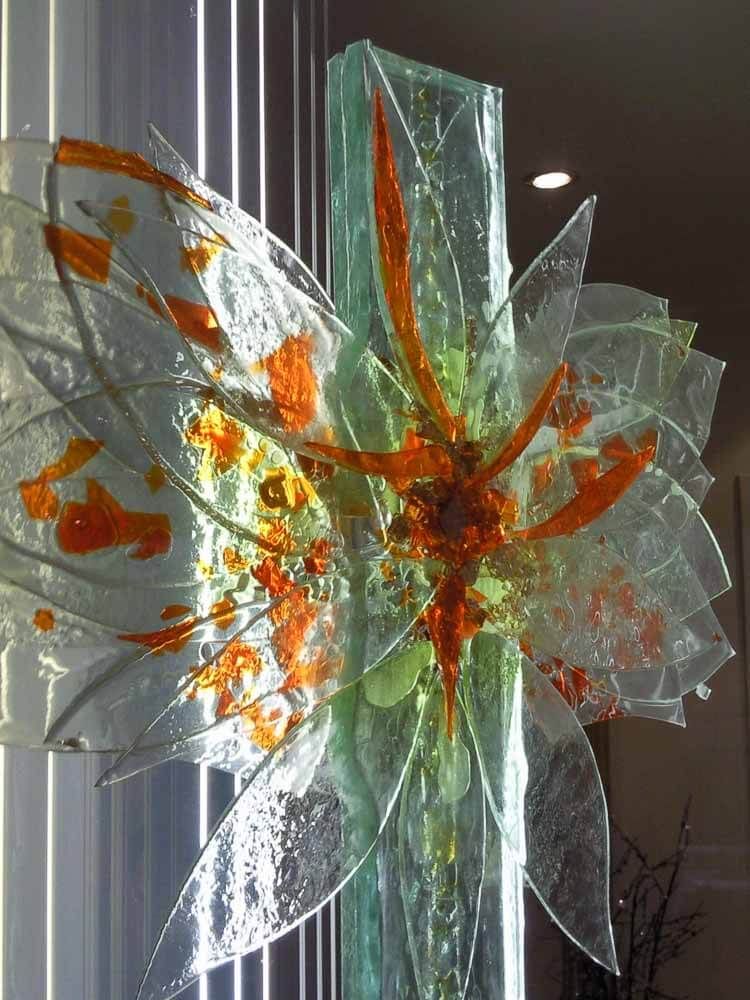 Sculpture en verre représentant une fleur abstraite aux teintes orange et vertes.