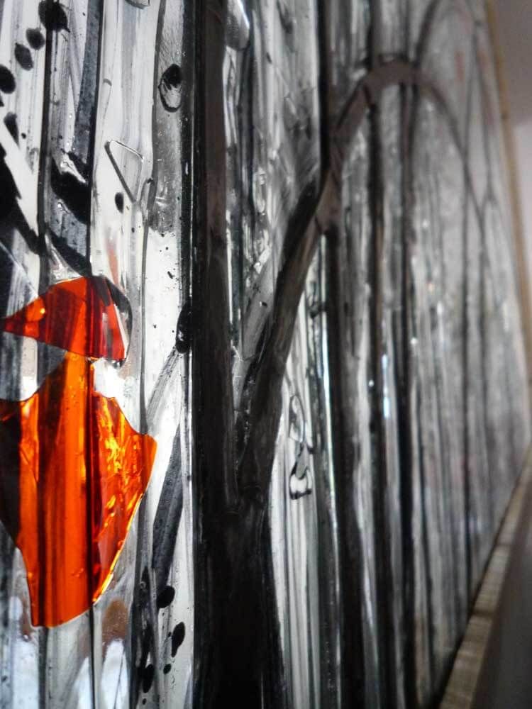 Art abstrait : formes orange et noires avec des lignes verticales noires ; vue partielle d'un vitrail.