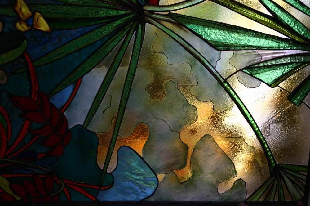 Vitrail représentant un feuillage tropical stylisé vert, bleu et or.