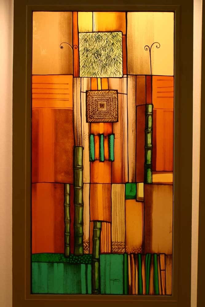 Vitrail abstrait composé de formes rectangulaires orange, vertes et dorées et d'éléments verticaux évoquant le bambou.