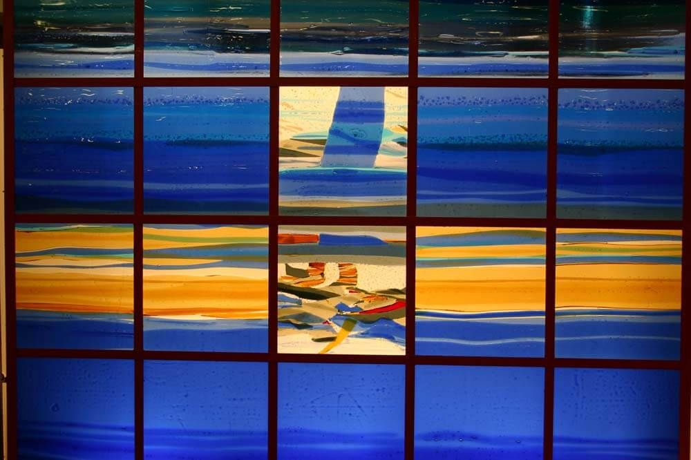 Vitrail aux teintes bleues et dorées ; paysage marin abstrait.