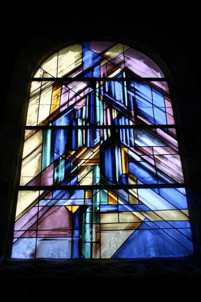 Vitrail abstrait aux formes géométriques bleues, roses et jaunes.